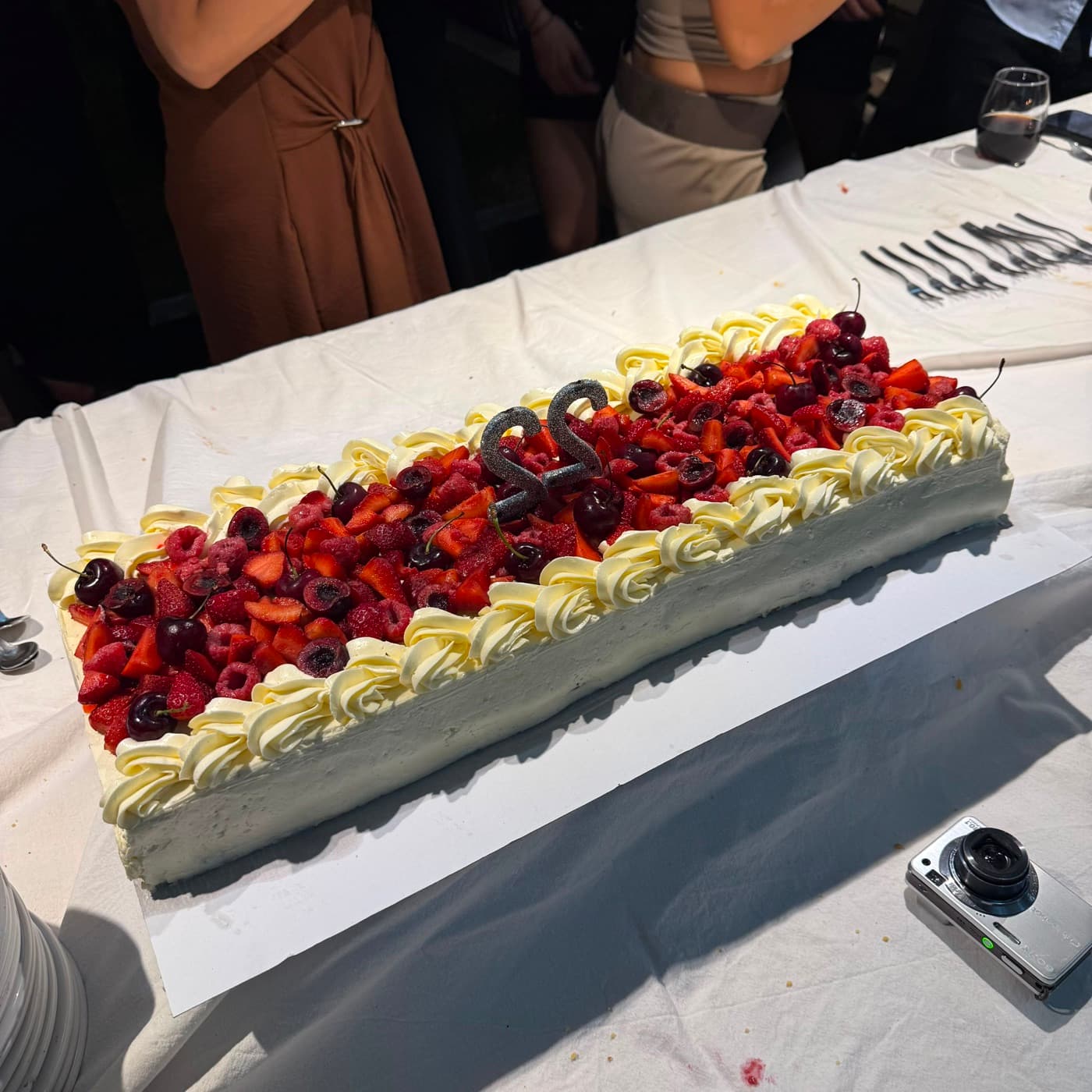 Torta de cumpleaños con frutos rojos sobre una mesa larga